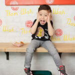 Toddler in his PiccoliNY x Nom Wah t-shirt with a look of surprise